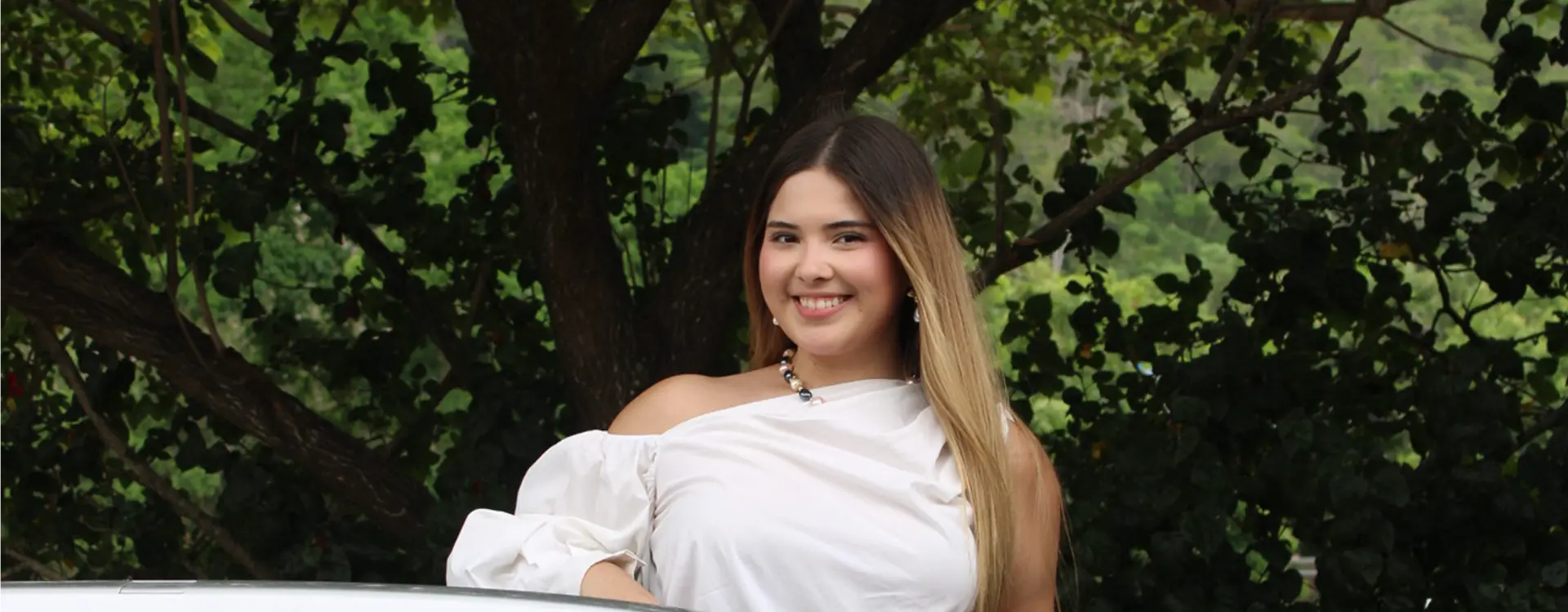 Clienta de SYGMA sonriendo junto a su vehículo asegurado